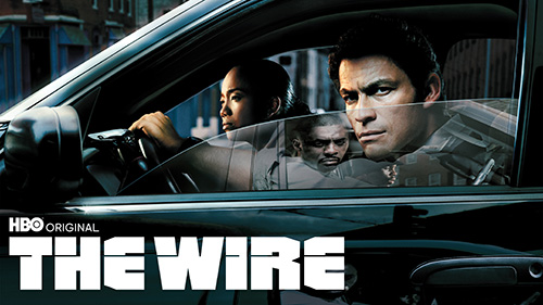 Advertisement for &quot;The Wire&quot; with actors portraying police officers in a car with the leaders of a drug organization in reflected in the window 