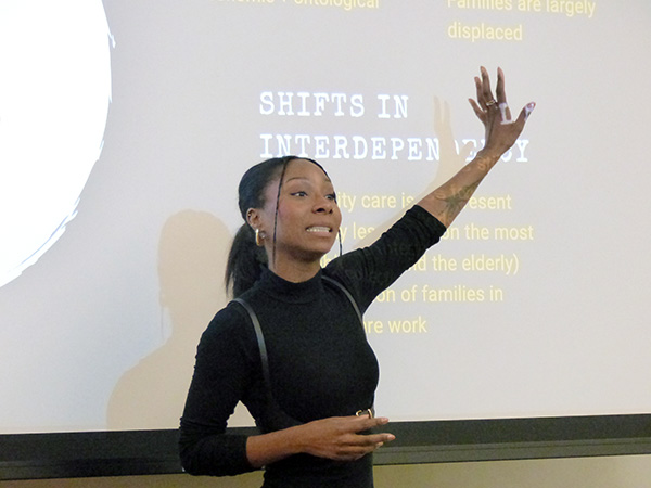 Kayla Thomas speaks in a classroom in front of a projections screen