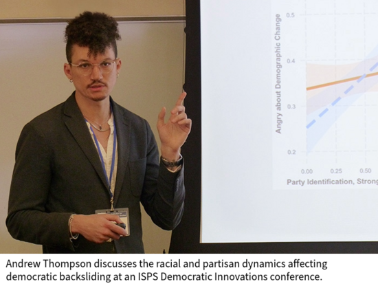 Andrew Thompson speaks in a classroom in front of a projection screen showing a chart.