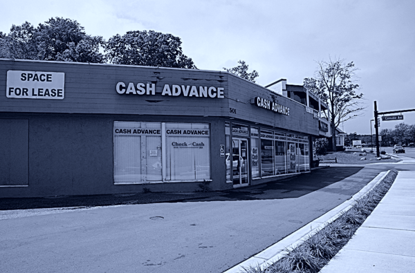 A corner store in a suburban setting with signs that say &quot;Cash Advance&quot; and &quot;Space for Lease&quot;