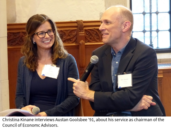 Christina Kinane listens as Austan Goolsbee speaks, as they sit on stools in a large wood-paneled room.