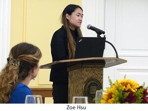 Zoe Hsu speaks from behind a lectern as people watch