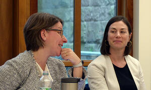 Eloise Pasachoff speaks at a table in a classroom as Rachel Augustine Potter listens