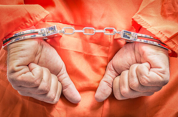 Handcuffed hands of a man in an orange jumpsuit