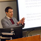 Samuel Bagg speaks in a classroom in front of a projection screen