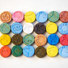 Several multi-colored pills of MDMA (Ecstasy) on white table